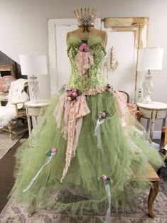 a dress made out of tulle with flowers and bows on the bust, sitting in front of a mirror