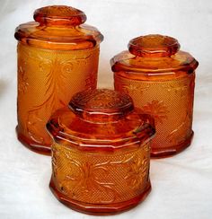 three orange glass jars are sitting next to each other