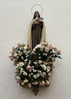 a statue of the virgin mary surrounded by flowers