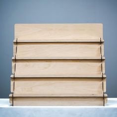 a stack of wooden boards sitting on top of a white tablecloth covered floor next to a gray wall