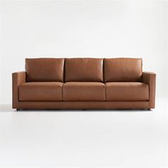 a brown leather couch sitting on top of a white floor