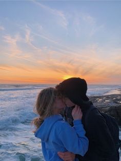 a man and woman standing next to each other near the ocean