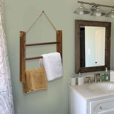 a bathroom with a sink, mirror and towel rack on the wall in front of it