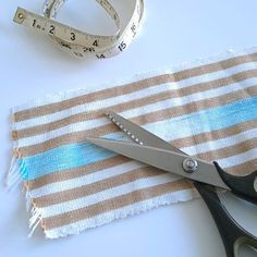 a pair of scissors sitting on top of a piece of fabric next to a measuring tape