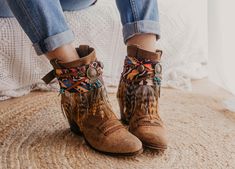 Step into the essence of Western charm with our handcrafted boot covers. Featuring a handmade suede braid and strip adorned with ancient Indian coins and natural khaki hair appliqué, topped with a central dream catcher in old gold. Embrace the spirit of the frontier with these unique and stylish boot accessories, perfect for adding a touch of rustic elegance to any ensemble. SPECIFICATIONS * Tribal boot covers * Made with multicolor ethnic printed scarf base and strip of feathers in beige tones Bohemian Leather Boots For Winter, Bohemian Moto Boots With Round Toe For Fall, Bohemian Suede Ankle Boots, Bohemian Moto Boots For Festival In Fall, Bohemian Ankle Boots For Winter, Bohemian Brown Winter Boots, Bohemian Winter Suede Boots, Bohemian Suede Winter Boots, Bohemian Brown Suede Boots