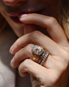 a close up of a person's hand with a ring on her finger and an engagement ring in the other hand