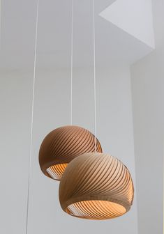 three wooden lamps hanging from the ceiling in a room with white walls and flooring