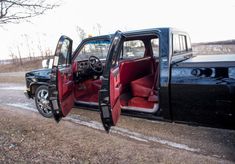 a black pickup truck with red seats in the back door and open doors on it's side