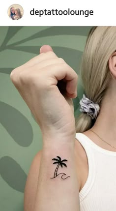 a woman with a small palm tree tattoo on her left arm and the word depattoolounge written in black ink