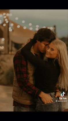 a man and woman embracing each other in front of christmas lights