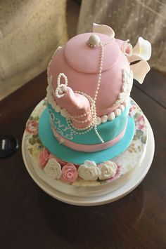 a three tiered cake decorated with pearls and pink, blue and white icing