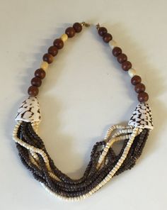 "This necklace has a beautiful carefree beach vibe! Pook a shell and wooden beads with two larger seashell beads on either side. What a great 1980's vintage summer staple.  This is a vintage used item and is in great vintage used condition with little to no wear, there are no missing or broken beads,  It is approximately 22\" in length." Vintage Brown Jewelry For The Beach, Vintage Brown Necklaces For The Beach, Vintage Brown Beaded Necklaces For Beach, Wooden Bead Necklaces For Vacation, Handmade Multi-strand Shell Necklace For Beach, Beach Necklaces With Colorful Beads In Brown, Adjustable Multi-strand Shell Necklace For Beach, Beaded Necklaces For Beach, Beaded Brown Necklace For Vacation