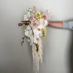 a bouquet of flowers is being held up by someone's hand on the wall