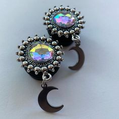 pair of black earrings with multicolored crystal stones and crescent moon charms on white background