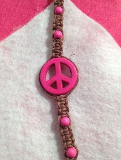 a pink peace sign on a brown bracelet