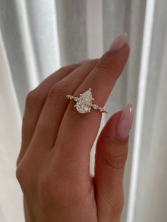 a woman's hand holding a diamond ring