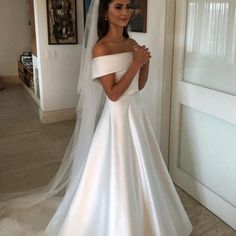 a woman in a white wedding dress standing next to a doorway with a veil on her head