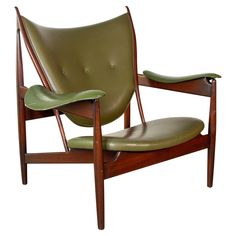 a green leather chair sitting on top of a wooden frame with arms and backrests