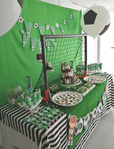 a soccer themed birthday party with green and black decorations, food and decorating on the table