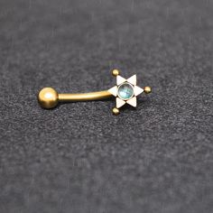 a gold nose ring with an aqua stone in the middle and a star design on it