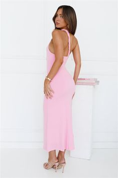 a woman in a pink dress posing for the camera with her hands on her hips