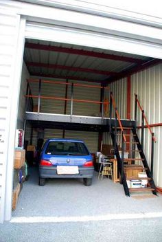 a blue car parked in front of a metal building with stairs leading up to it