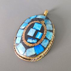 A unique handcrafted piece of Artisan Necklace pendant  It features a stunning inlay mosaic design in shades of blue, set against brass.  In good vintage condition. Traditional Blue Patina Necklace, Collectible Blue Inlay Necklace, Artisan Blue Inlay Necklaces, Unique Blue Necklace With Inlay, Antique Blue Brass Necklace, Antique Blue Jewelry With Patina, Antique Blue Patina Jewelry, Traditional Blue Inlay Necklaces, Traditional Blue Necklaces With Inlay