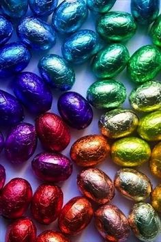 many different colored chocolate eggs on a white surface