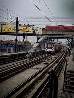 a train traveling down tracks next to a tall building