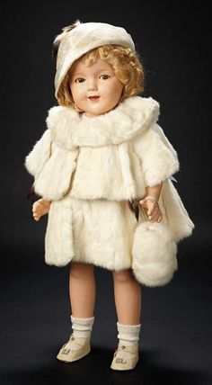 an old doll wearing a white fur coat and hat with her hands in her pockets