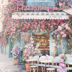 the outside of a restaurant with tables and chairs covered in pink flowers on the front