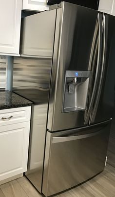 a stainless steel refrigerator with water dispenser on the door in a kitchen