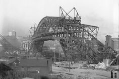 an old black and white photo of a bridge being built in the middle of town