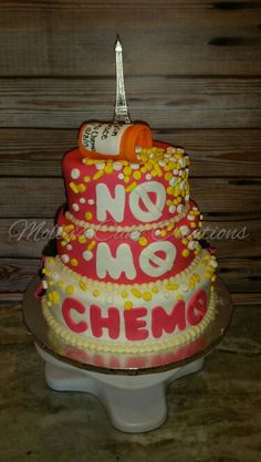 there is a cake that says no me and chemo on the bottom tier, with an eiffel tower in the background