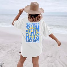 a woman standing on the beach wearing a t - shirt that says boat waves, sun rays, and lake days