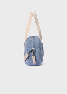 a small blue bag with two straps hanging from it's shoulder and the front pocket open