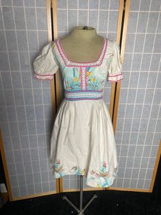 "Vintage 1970's cottage core cute puffy sleeves summer dress with ric rac and lace trim. Flower prints on hem and bodice. Extra small In great vintage condition. Women's size xs 34\" bust 24\" waist free hips up to 46\" 13.5\" shoulder to waist 22.75\" waist to hem" Puff Sleeve Dress With Lace Trim For Garden Party, Summer Cottagecore Puff Sleeve Dress With Ruffles, Fitted Peasant Dress With Smocked Bodice For Spring, Cottagecore Summer Puff Sleeve Dress With Ruffles, Cute Fitted Puff Sleeve Dress With Floral Print, Spring Puff Sleeve Dress With Lace Trim, Cottagecore Puff Sleeve Dress With Square Neck, Spring Square Neck Puff Sleeve Dress With Lace Trim, White Puff Sleeve Empire Waist Dress For Spring