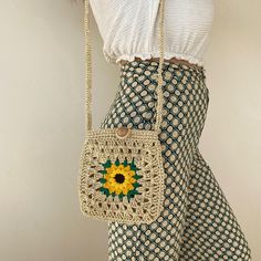 a crocheted bag with a sunflower on it hanging from a woman's waist