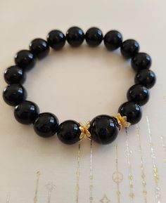 This sleek and timeless black onyx bracelet is not only a bold fashion statement but also a powerful source of protection and grounding. The smooth, polished onyx beads in a deep, jet-black tone symbolize strength and resilience, helping to ward off negative energy and bring emotional stability. Featuring delicate gold-tone accents, this bracelet adds a touch of luxury to its minimalist design, making it perfect for both casual and formal wear. Our handcrafted stone bracelets are more than just beautiful accessories--they carry the energy of nature to inspire balance, courage, and mindfulness in your daily life. Each bracelet is made with high-quality, natural stones known for their healing properties.  We believe in giving back to the community, which is why we donate every bracelet sold Elegant Obsidian Bracelets For Meditation, Elegant 8mm Beads Crystal Bracelet For Meditation, Elegant Crystal Bracelet With 8mm Beads For Meditation, Elegant 8mm Beads Bracelet For Meditation, Elegant 8mm Beaded Crystal Bracelet For Meditation, Onyx Crystal Bracelet With Black Round Beads, Elegant Gemstone Beads Stretch Bracelet For Meditation, Elegant Black Rosary Bracelet, Black Agate Bracelets For Healing