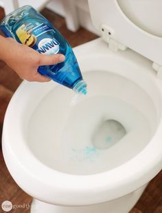 a person is cleaning a toilet with a blue bottle and toothpaste on it