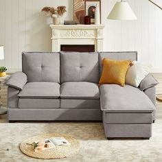 a living room with a sectional couch and pillows on the floor in front of a fireplace