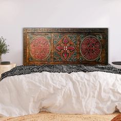 a bed with white sheets and an intricately decorated head board on top of it