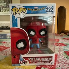 a red spider - man pop vinyl figure in a box on a table with flowers