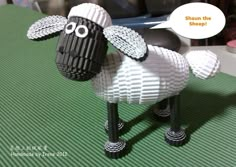 a black and white sheep made out of legos on a green surface with a speech bubble above it