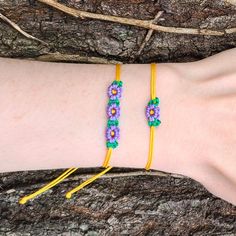 a woman's arm with two bracelets on it, one is yellow and the other is purple