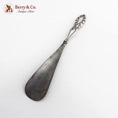 a silver spoon with an ornate handle on a white surface, and the words berry & co written below it