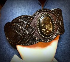 "\"Out of the dark\" is a hand tooled and hand painted leather bracelet with iridescent seraphinite cabochon. It was made to fit the 7 1/2\" (19cm) wrist. This particular cuff was MADE TO ORDER. If you would like me to design something for you welcome to place a custom order and we will discuss a design, which would match your personality. I've got plenty of different gemstones in stock, thus I believe we would find something just for you. Once the order is ready it will be shipped to you by pri Unique Hand Tooled Black Jewelry, Handmade Black Artisan Leather Bracelet, Handmade Artisan Black Leather Bracelet, Black Artisan Handmade Cuff Bracelet, Artisan Leather Bracelet With Patina Gift, Artisan Handmade Black Cuff Bracelet, Handmade Artisan Black Cuff Bracelet, Handmade Adjustable Cuff Bracelet, Formal Handmade Leather Jewelry