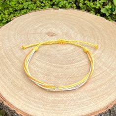 a yellow and white bracelet sitting on top of a tree stump