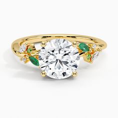 a yellow gold engagement ring with an emerald and white diamond accented in green leaves