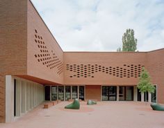 an empty courtyard in front of a brick building with geometric designs on the wall and floor